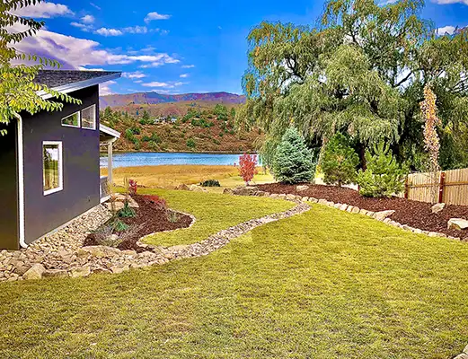 large lawn and cobble river with newly installed trees in Durango
